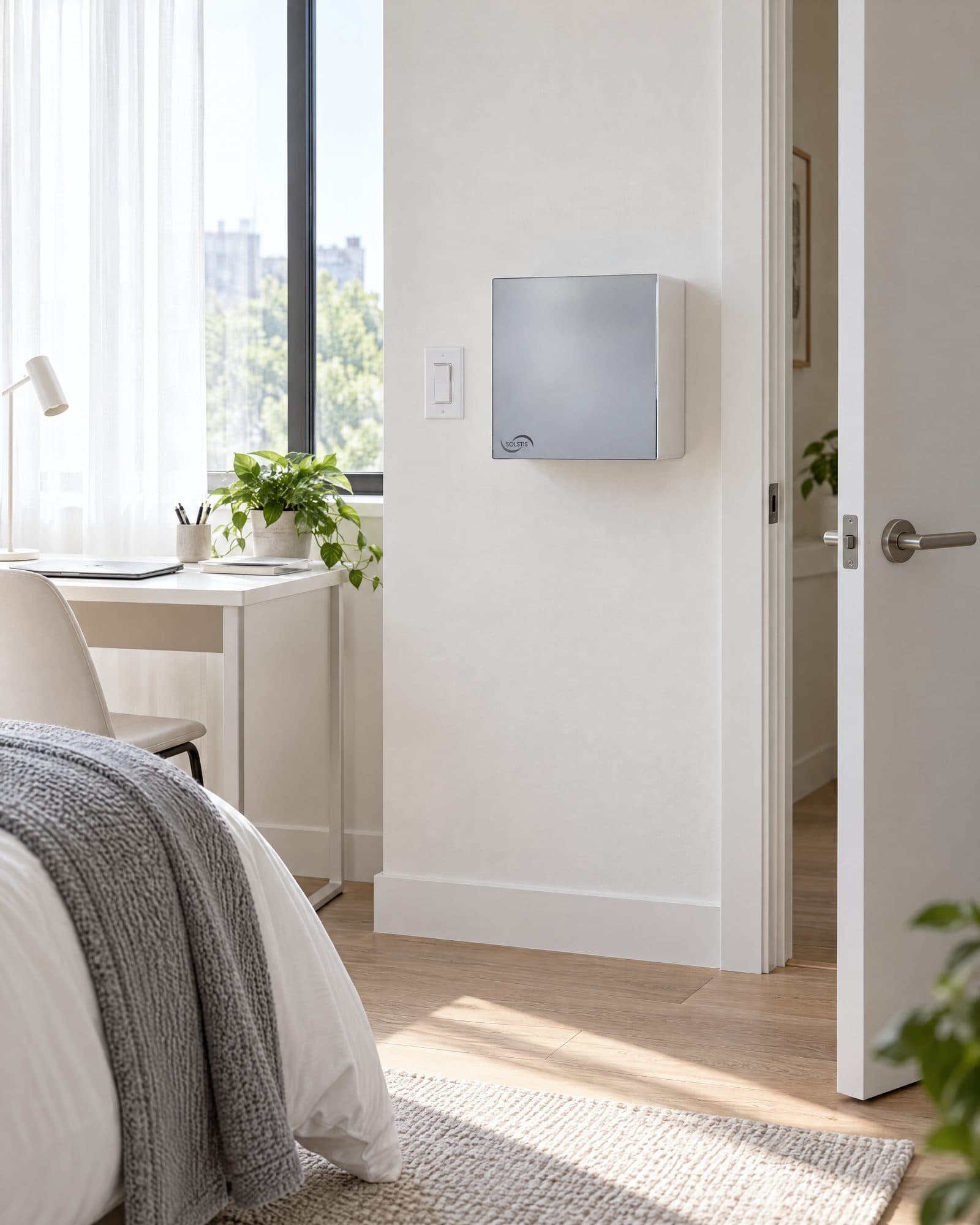 A bright student apartment bedroom with the closed Solstis cabinet on the wall beside the bedroom door, next to the light switch.