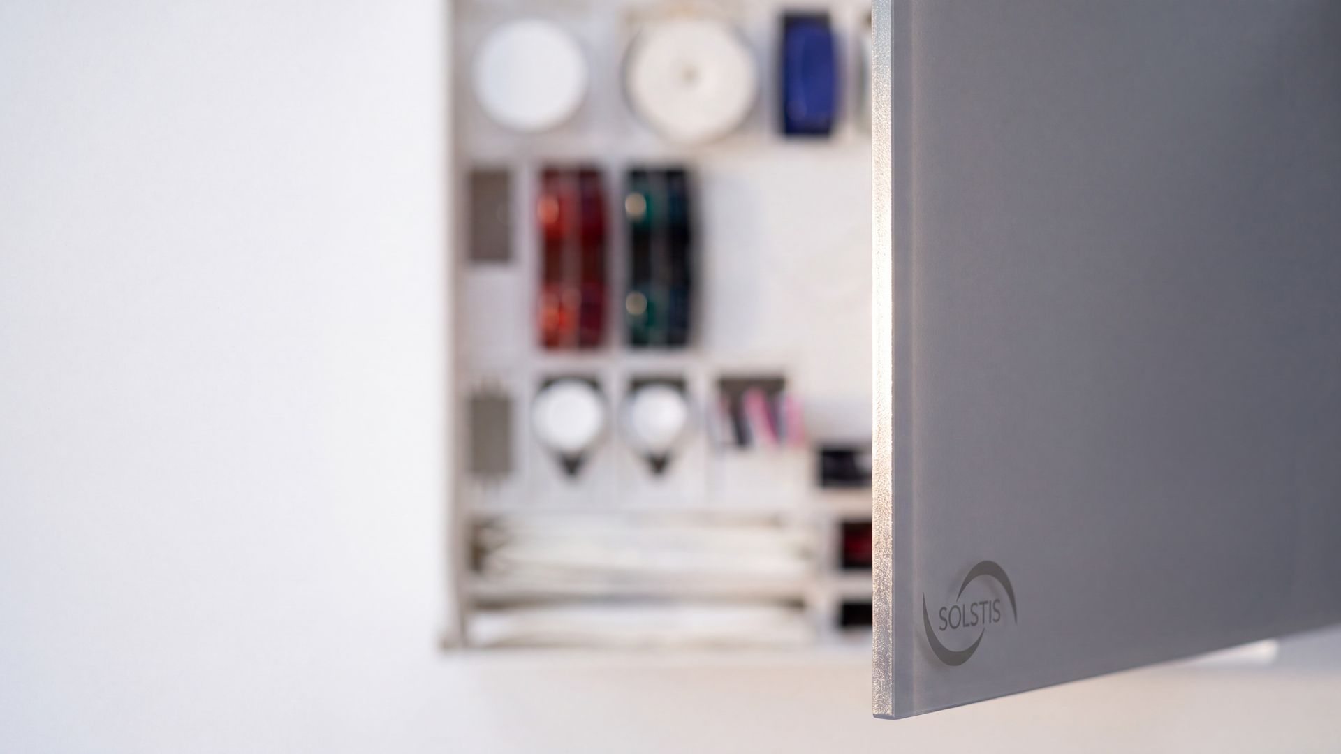 Close up: the edge of the Solstis cabinet's door, swung open, the stocked compartments soft behind it.
