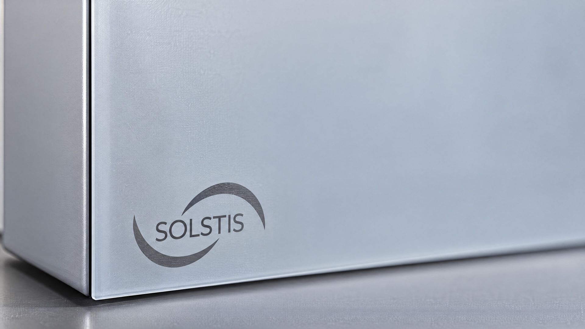 Close up: the lower corner of the closed Solstis cabinet, its frosted door marked with the Solstis logo.